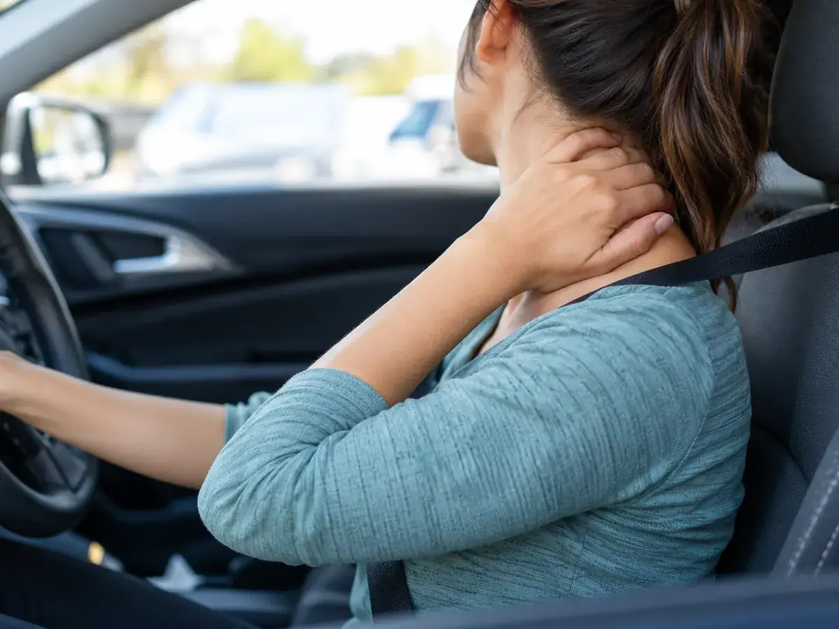Driver holding her neck while wearing a seatbelt
