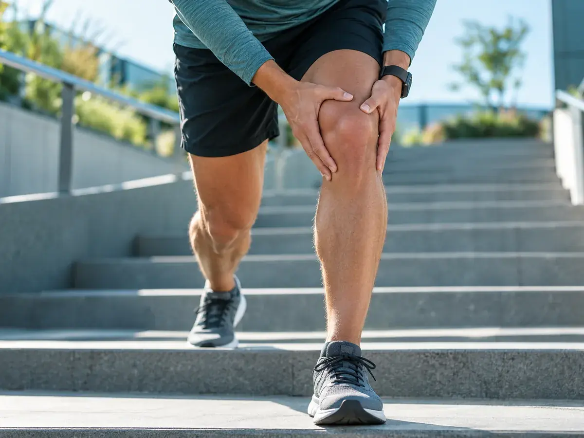 Runner holding his knee on outdoor stairs